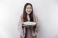 A smiling Asian Muslim woman is fasting and hungry and holding and pointing to a plate