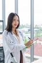 Smiling asian nutritionist doctor woman writing on paper green board in laboratory room Royalty Free Stock Photo