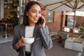 Smiling Asian professional woman talking on cell phone standing outside office. Royalty Free Stock Photo