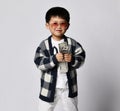 Smiling asian rich kid boy millionaire in sunglasses and plaid cardigan holds dollars cash money with both hands. Lucky winner