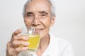 Smiling asian senior woman is drinking a glass of vitamin C,orange juice,old elderly with effervescent vitamin C,strengthening the Royalty Free Stock Photo