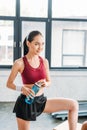 smiling asian sportswoman with bottle of water