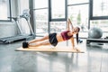 smiling asian sportswoman doing side plank on fitness mat