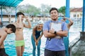 a smiling asian swimming trainer holding a clipboard and stopwatch