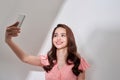 Smiling asian taking a selfie with smartphone on white background