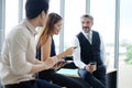 Smiling Asian team and Senior Caucasian businesspeople teamwork relaxing and brainstorm. Businesswoman holding smartphone and