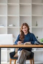 Smiling asian undergraduate teen girl student study in library with laptop books doing online research for coursework Royalty Free Stock Photo