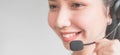 Smiling Asian woman consultant wearing microphone headset of customer support phone operator at workplace. Royalty Free Stock Photo