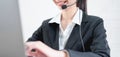 Smiling Asian woman consultant wearing microphone headset of customer support phone operator at workplace. Royalty Free Stock Photo