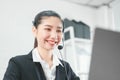 Smiling Asian woman consultant wearing microphone headset of customer support phone operator at workplace. Royalty Free Stock Photo