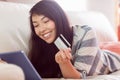 Smiling asian woman on couch using tablet to shop online Royalty Free Stock Photo