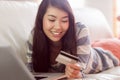 Smiling asian woman on couch using tablet to shop online Royalty Free Stock Photo