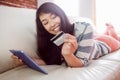 Smiling asian woman on couch using tablet to shop online Royalty Free Stock Photo