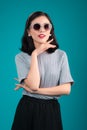 Smiling asian woman dressed in pin-up style dress wearing eyeglasses over blue. Royalty Free Stock Photo