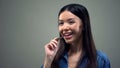 Smiling asian woman enjoying taste of chocolate, standing on grey background