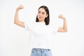 Smiling asian woman, flexing biceps, looking sassy and strong, showing her strength muscles, white studio background Royalty Free Stock Photo
