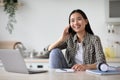 Smiling asian woman freelancer talking on phone and using laptop Royalty Free Stock Photo