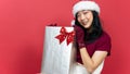 Smiling asian woman holding big giftbox over red background. Concept of the New Year and Christmas Day Royalty Free Stock Photo