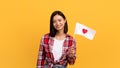 Smiling asian woman holding flag with heart on yellow background Royalty Free Stock Photo