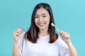 Smiling Asian woman holding orthodontic retainer on blue screen background. Dental care and teeth Royalty Free Stock Photo