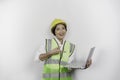 A smiling Asian woman labor wearing safety helmet and vest while holding her laptop, isolated by white background. Royalty Free Stock Photo