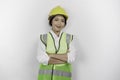 Smiling Asian woman labor worker in industry factory, posing with arms folded, wearing yellow safety helmet, green vest and Royalty Free Stock Photo