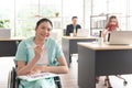 Smiling Asian woman office worker in wheelchair hold pencil look at camera, disabled people working with colleague at workplace Royalty Free Stock Photo