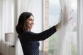 Smiling asian woman open curtains looking in distance Royalty Free Stock Photo