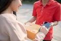 A smiling Asian woman receiving a package from a delivery man at home Royalty Free Stock Photo