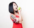 Smiling asian woman red dress biting green apple on white Royalty Free Stock Photo