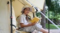 Smiling asian woman resting, reading a book in camping tent. Travel, camping and vacation concept Royalty Free Stock Photo