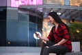 Smiling woman sitting on bench in a city and using smart phone. Royalty Free Stock Photo