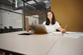 Smiling Asian woman sitting at the desk while looking to the screen of computer Royalty Free Stock Photo