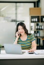 Smiling Asian woman talking on the phone with a customer Young positive female accountant using smartphone talking to team at her Royalty Free Stock Photo