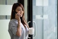 Smiling asian woman talking on the phone at home, happy young girl holds cellphone making answering call, attractive Royalty Free Stock Photo