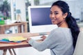 Smiling Asian woman using computer looking back at the camera Royalty Free Stock Photo