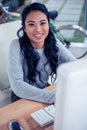 Smiling Asian woman using computer and looking at the camera Royalty Free Stock Photo