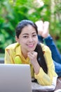 Smiling asian woman using laptop computer with earphones and loo Royalty Free Stock Photo