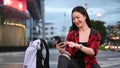 Smiling woman using smart phone while sitting on stairs in city at night. Royalty Free Stock Photo