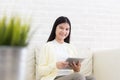 Smiling asian woman using tablet on sofa at home in the living room Royalty Free Stock Photo