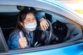 Smiling asian woman wearing mask thumbs up protective germs