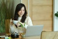 Smiling woman wearing warm sweater and drinking hot coffee while using laptop computer a home. Royalty Free Stock Photo