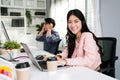 Smiling Asian woman working as customer support operator with headset in a call center. Portrait of sales agent sitting at desk Royalty Free Stock Photo