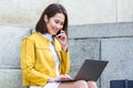 Smiling asian woman working on laptop computer while sitting on the floor and talking on her smart phone. Asian woman talking on Royalty Free Stock Photo