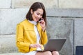 Smiling asian woman working on laptop computer while sitting on the floor and talking on her smart phone. Asian woman talking on Royalty Free Stock Photo