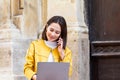 Smiling asian woman working on laptop computer while sitting on the floor and talking on her smart phone. Asian woman talking on Royalty Free Stock Photo