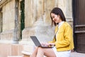 Smiling asian woman working on laptop computer while sitting on the floor and talking on her smart phone. Asian woman talking on Royalty Free Stock Photo