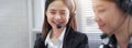 Smiling Asian woman consultant wearing microphone headset of customer support phone operator at workplace. Royalty Free Stock Photo