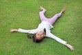 Smiling Asian young girl child lying on green lawn at the garden. Kid lies on grass with looking camera Royalty Free Stock Photo