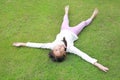 Smiling Asian young girl child lying on green lawn at the garden. Kid lies on grass with looking camera Royalty Free Stock Photo